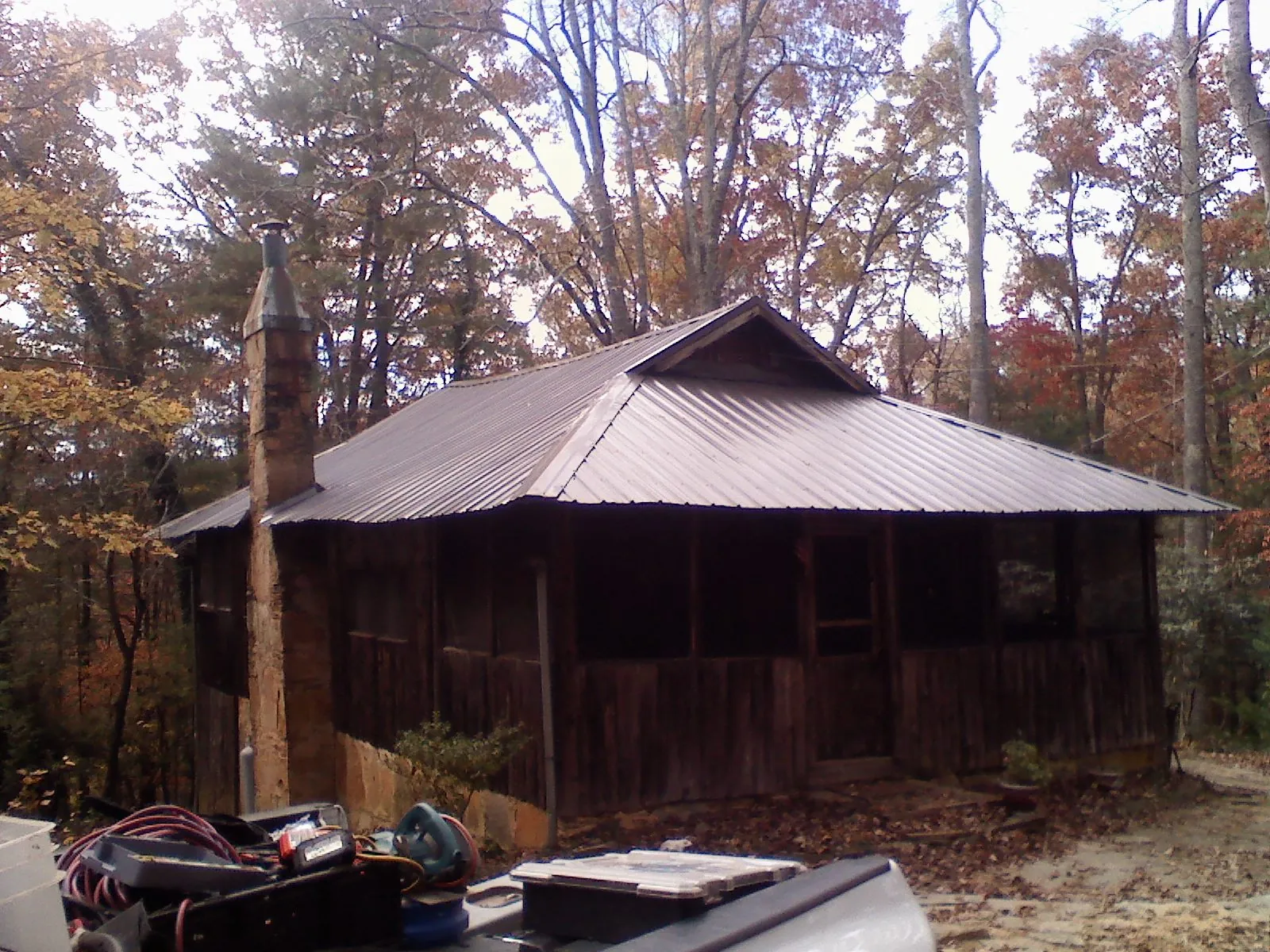 Brown metal hip roof on an old cabin with a stone chimney in Blue Rapids