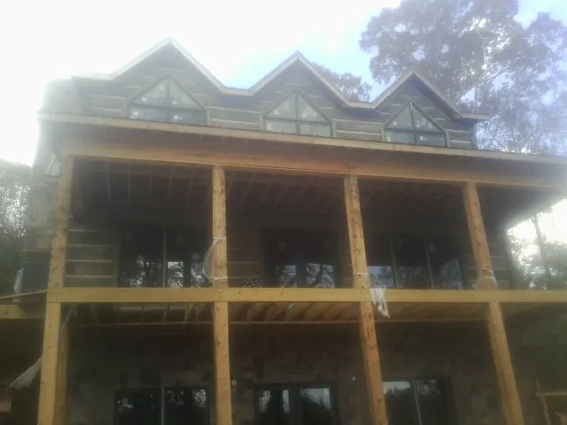 Dormers and porch framing on a large log home under construction — Roof Coating work by our crew in Blue Rapids