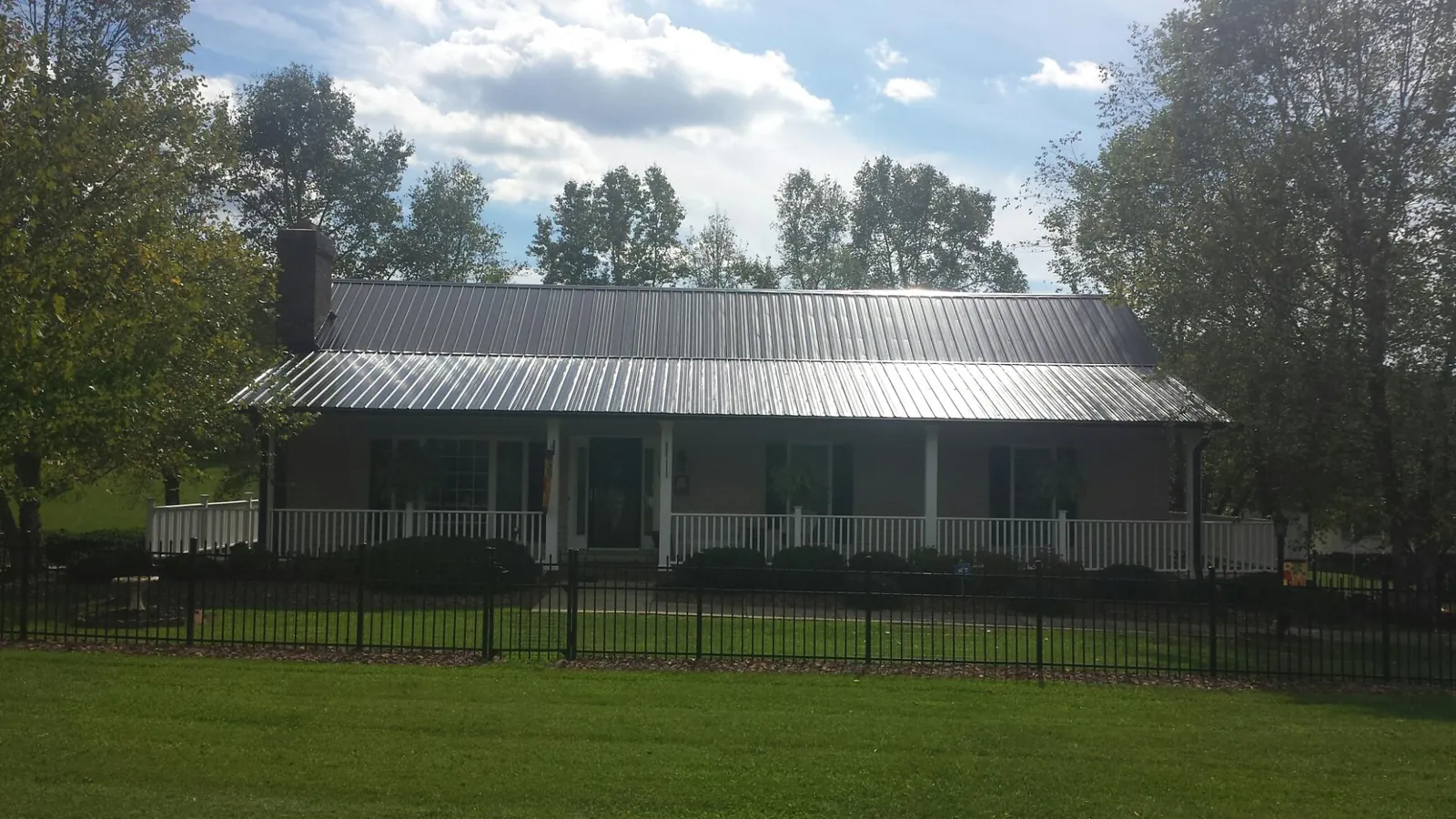 Gray metal roof on a brick ranch with a full width front porch — Gutter Guard Installation work by our crew in Blue Rapids
