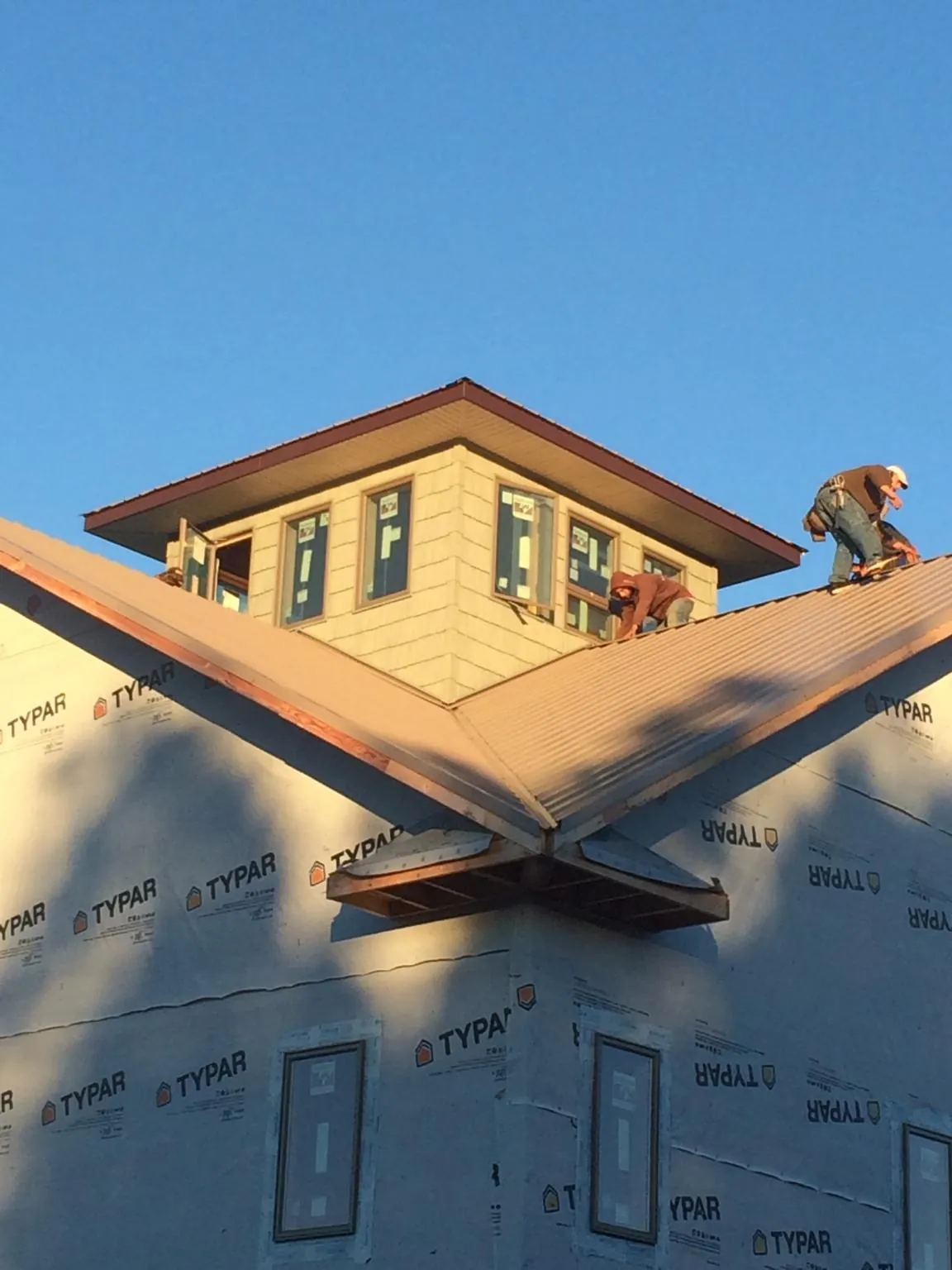 Roofers working around a rooftop cupola on a new metal roof at sunset — Roof Waterproofing in Blue Rapids by Roofing Brothers